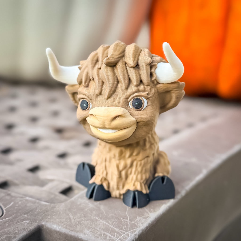Small brown creature figurine with large horns on a textured surface