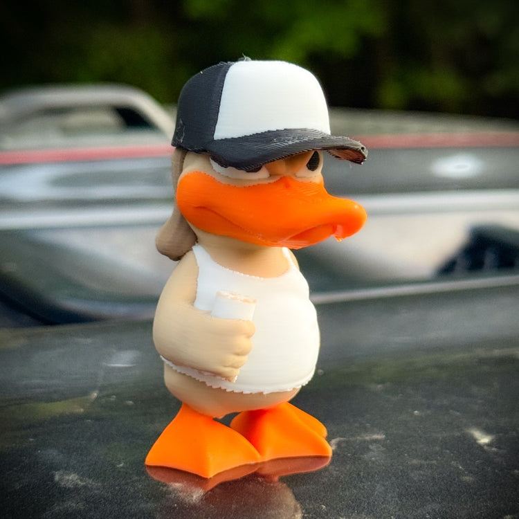 Bubba Duck by FirstWarrior is a small 3D-printed duck in a white tank top and black-and-white cap, holding a white object outdoors with greenery behind—a perfect accessory for DuckDuckJeep fans.