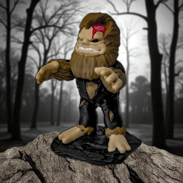 The FirstWarrior Undead Bigfoot figurine features a red forehead wound and stands on a rock, set against a foggy forest—an ideal unique Jeep dash accessory for adventurous spirits.