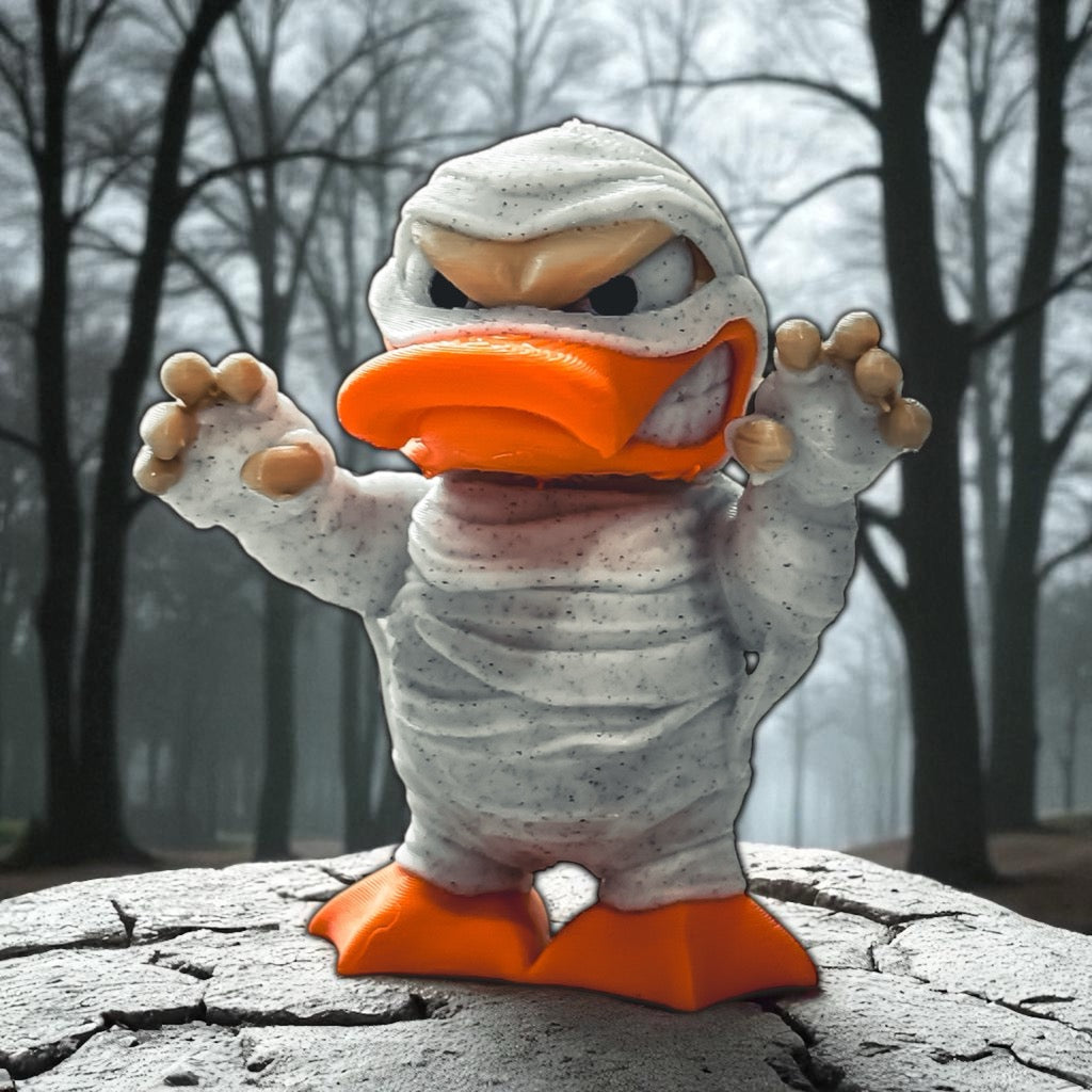 Mummy-themed duck figurine with orange beak and feet in a forest setting