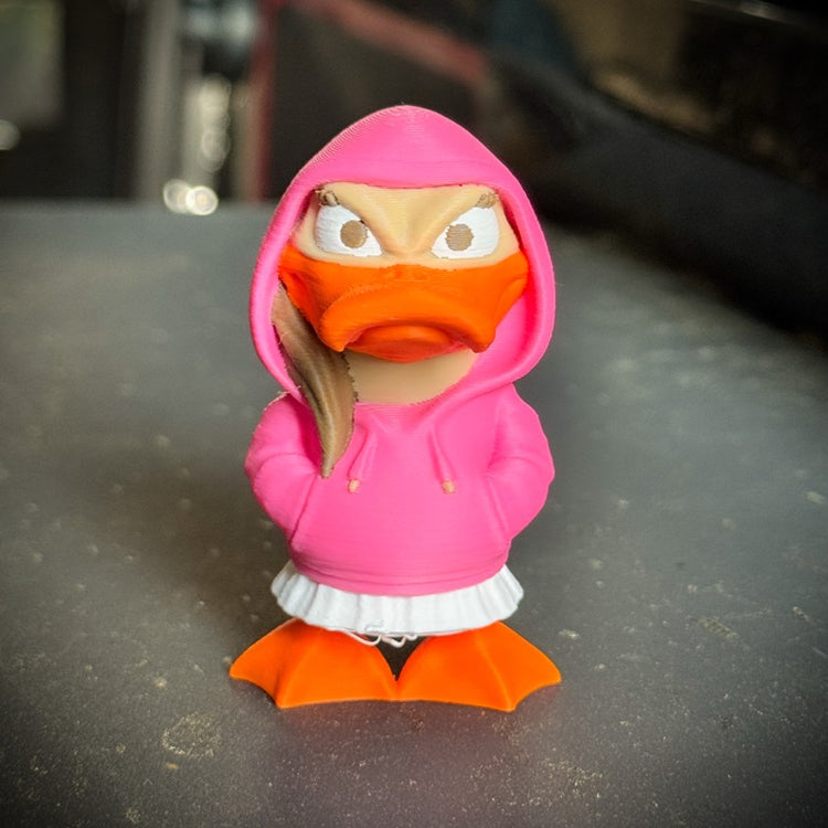 Toy figure of a character wearing a pink hoodie and orange outfit on a dark surface