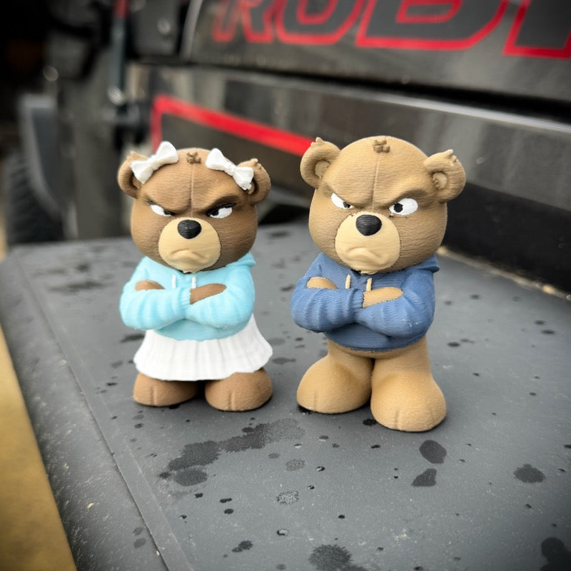 Two teddy bear figurines in front of a vehicle with 'Rodeo' branding.