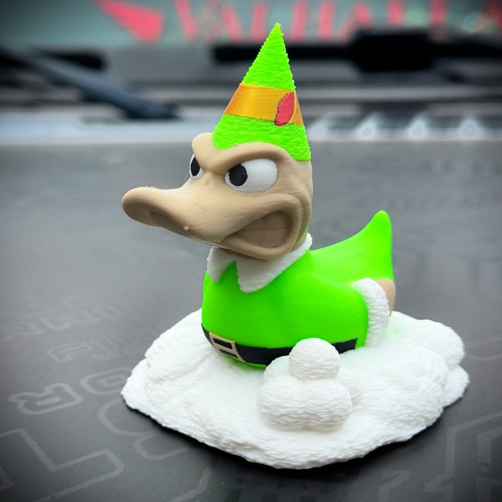 Buddy the Duck by FirstWarrior is an ELF-themed figurine with an angry face, dressed in a green elf costume and pointed hat on a snowy base—ideal as quirky Christmas decor or a fun car dashboard accessory.