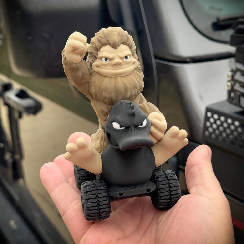 Two toy figures, one resembling a gorilla and the other a duck, held in front of a car interior.