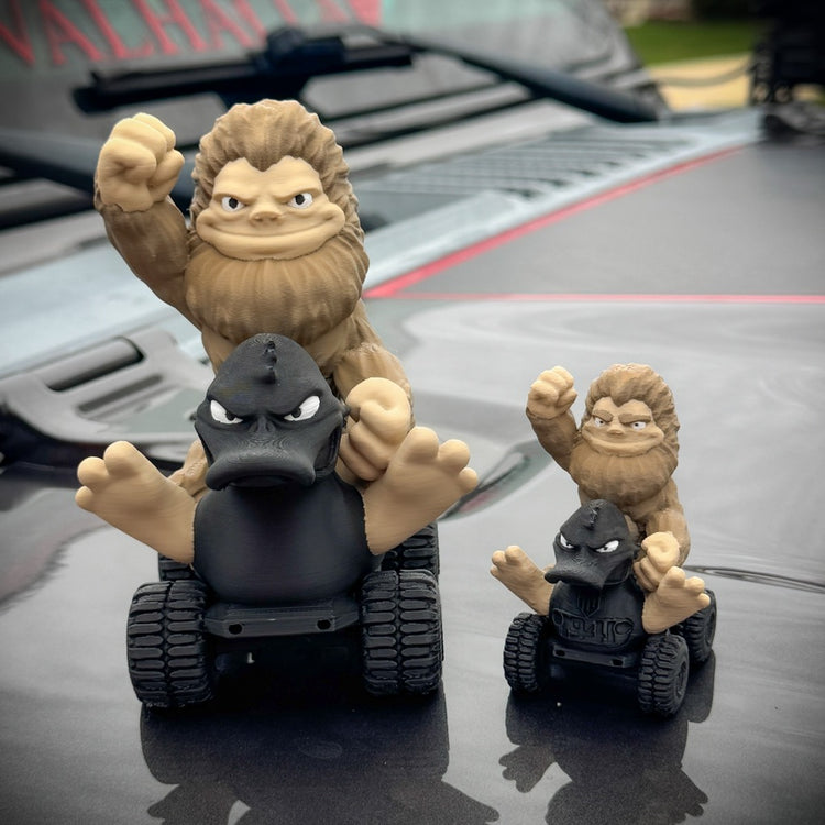 Three toy figures of gorillas on vehicles with a car in the background