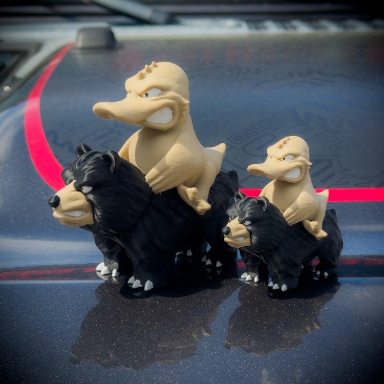 Three cartoon duck and bear figurines on a car hood