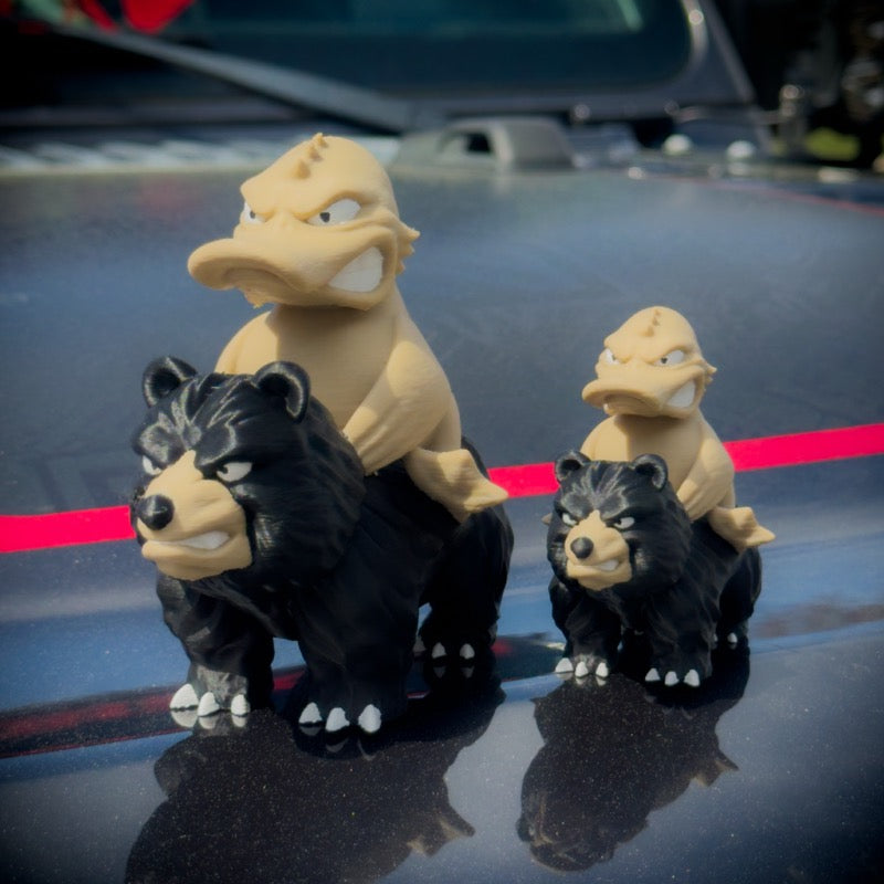 Three toy figures of a bear and a dragon on a car hood
