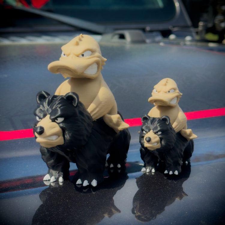 Three toy figures of a bear and a dragon on a car hood