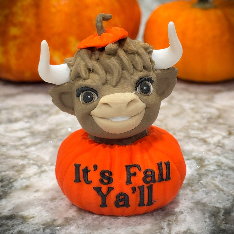 Pumpkin-shaped toy with a bull head and 'It's Fall Ya'll' text, surrounded by pumpkins.